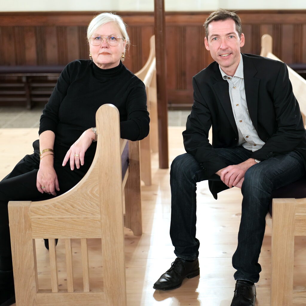 Dorte Wassard and Jacob Würtzen, sitting on the church pews they have designed for Sion's Church in Copenhagen, 2022.